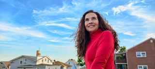 Smiling woman in front of a blue sky and houses