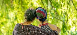 Two women looking at green trees, pictured from behind