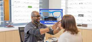 An optician helps a patient with glasses