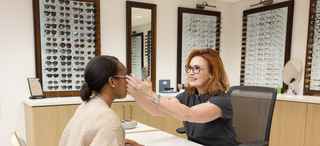 Optician helps patient with glasses