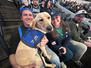 facility dog Tia with three people at basketball game
