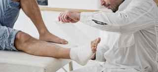 Doctor bandages a patient's ankle