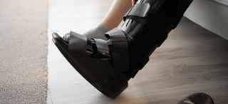 A person wearing a black orthopedic walking boot on their lower leg and foot.