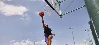 Woman shooting a layup on an outdoor basketball court