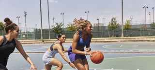 Women playing basketball on an outdoor court