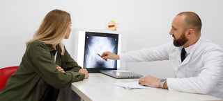 Doctor pointing at x-ray of pelvis with patient looking on