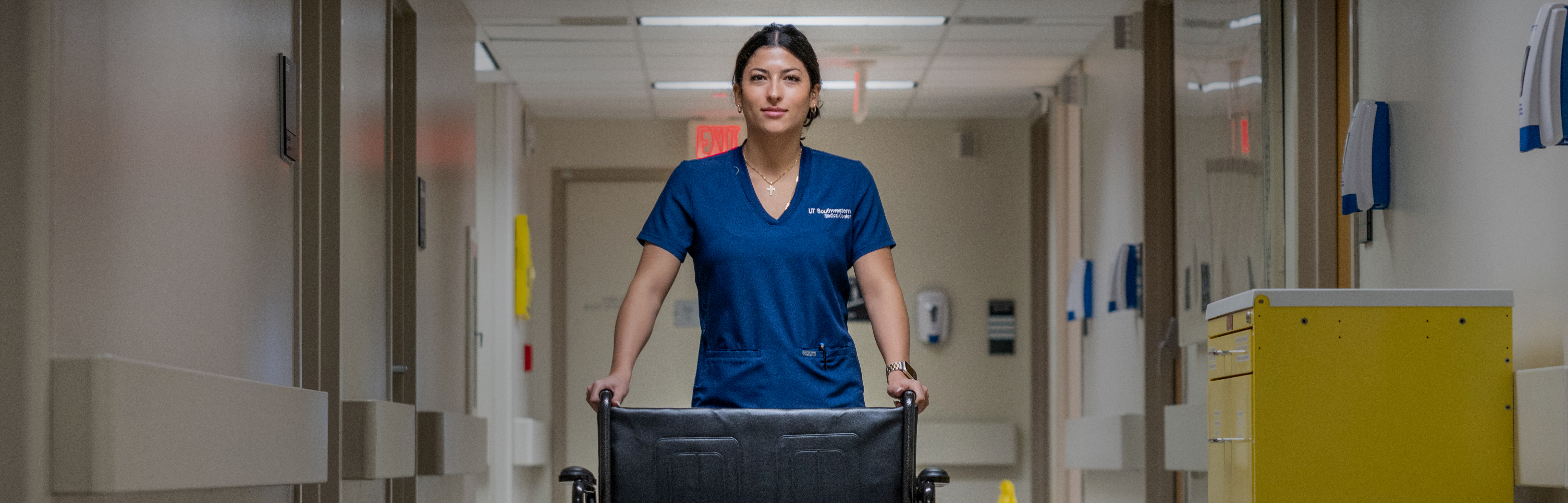 Nurse in blue scrubs pushing a wheel chair