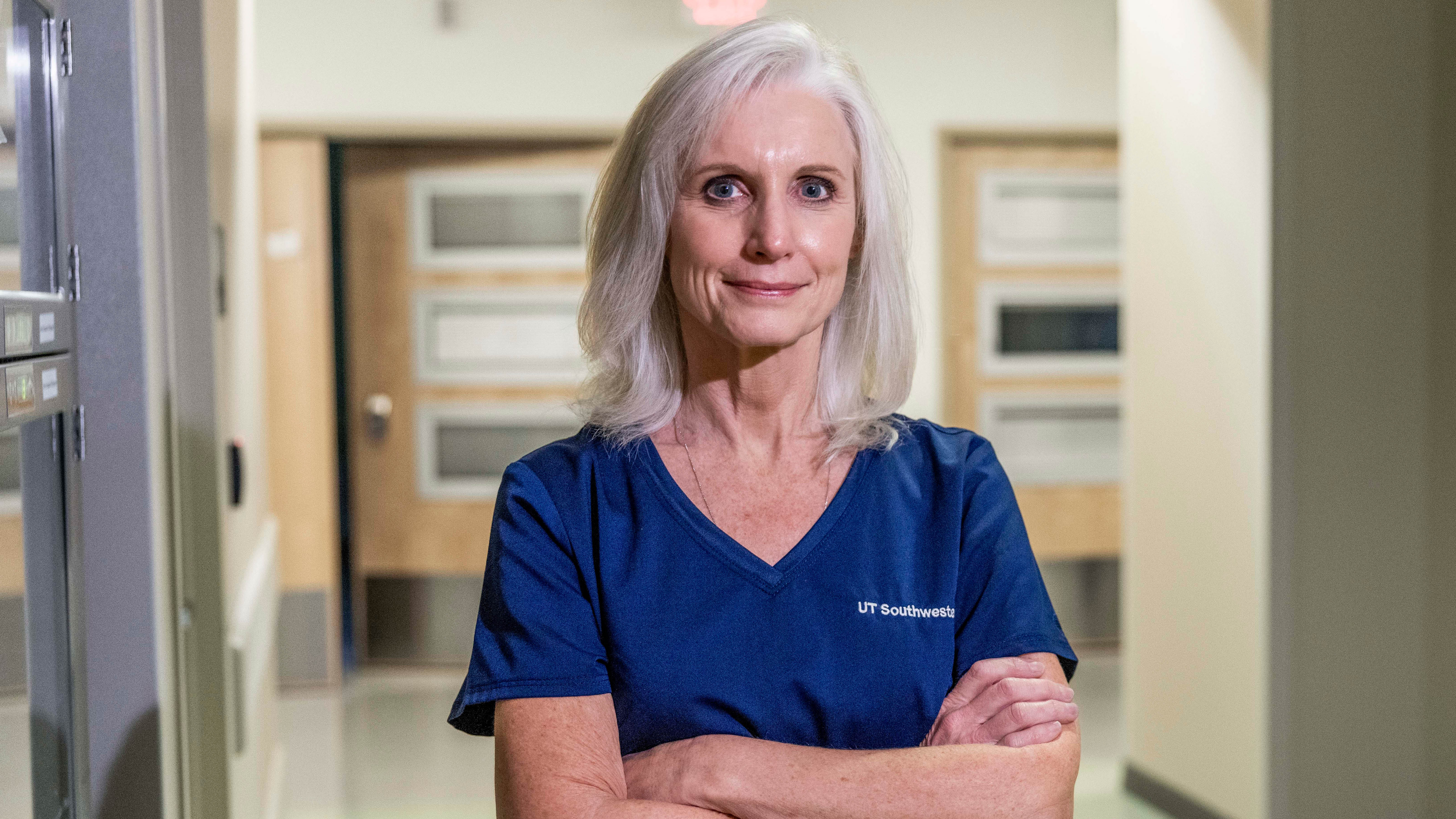 Female nurse standing in a hallway with crossed arms