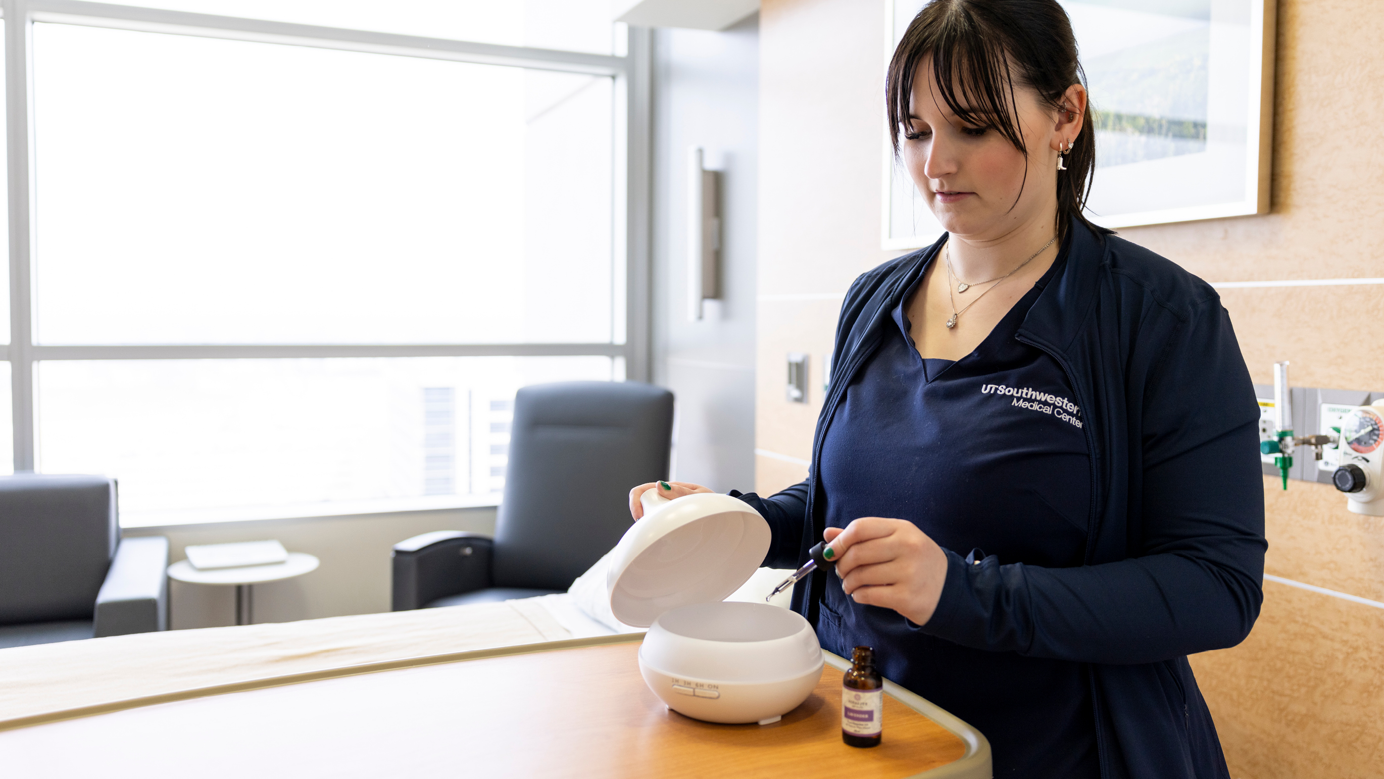 Nurse adding essential oil to a diffuser.