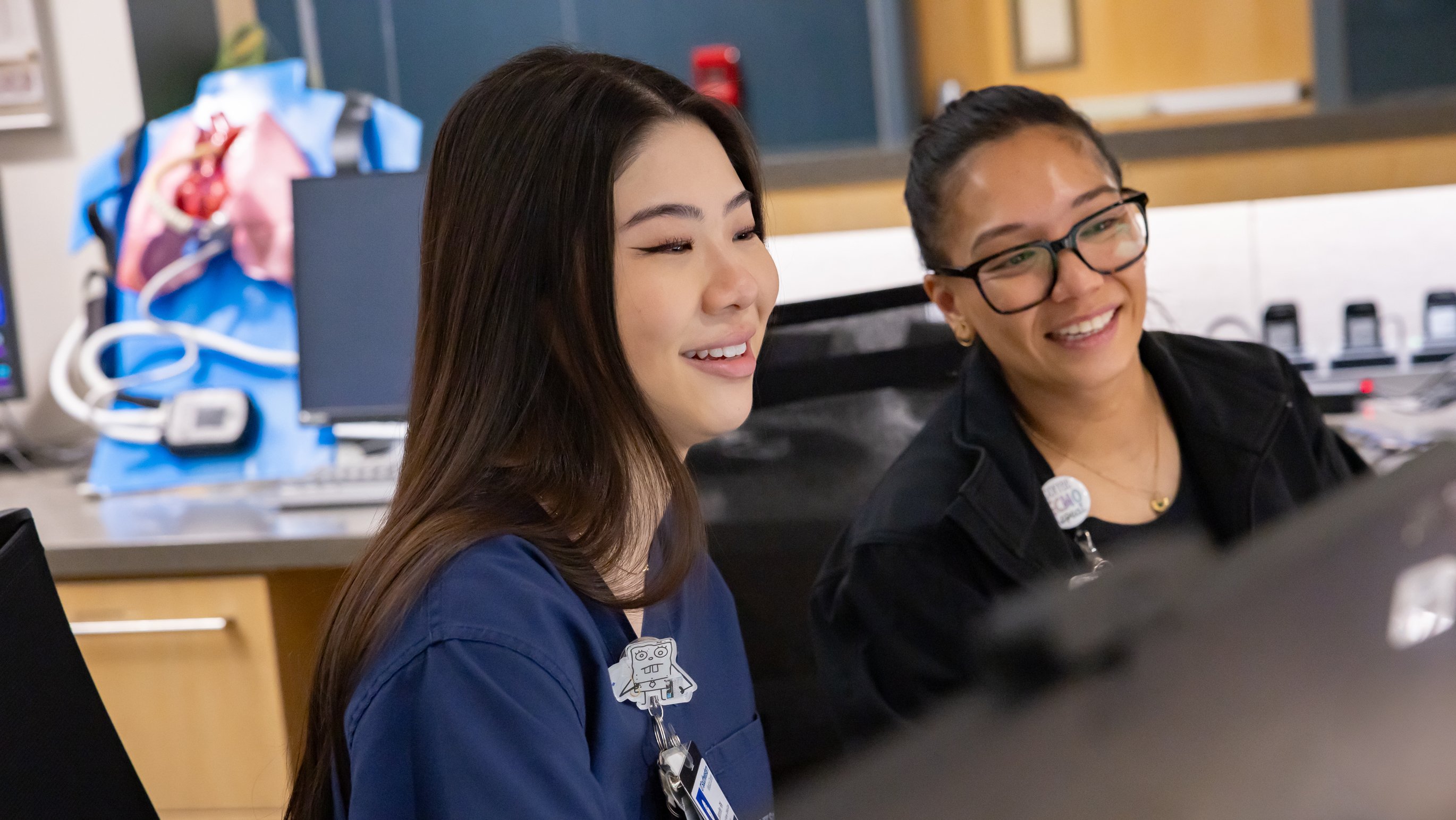 Two nurses smiling behind a desk