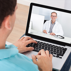A man is having a video consultation with a doctor on a laptop.