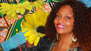 Artist Barbara Mason with her brightly colored artwork pictured in background.