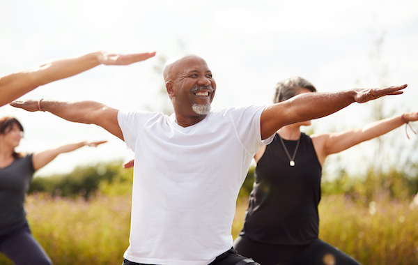 Man doing arm exercises as part of yoga class outdoors