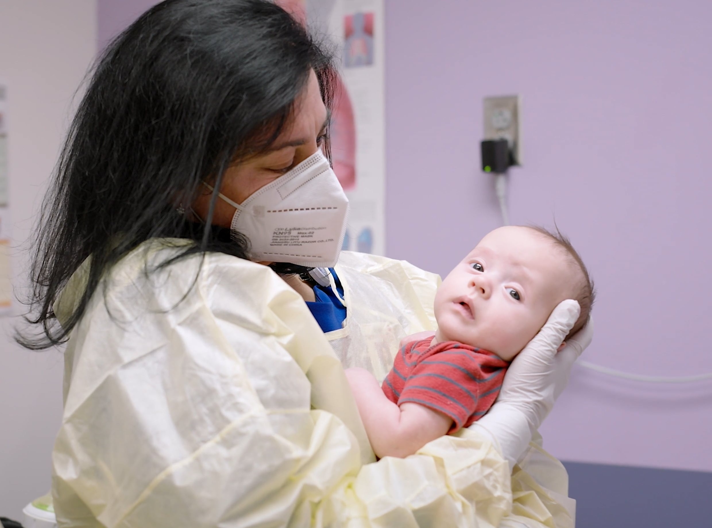 Medical provider wearing PPE holding baby in hospital