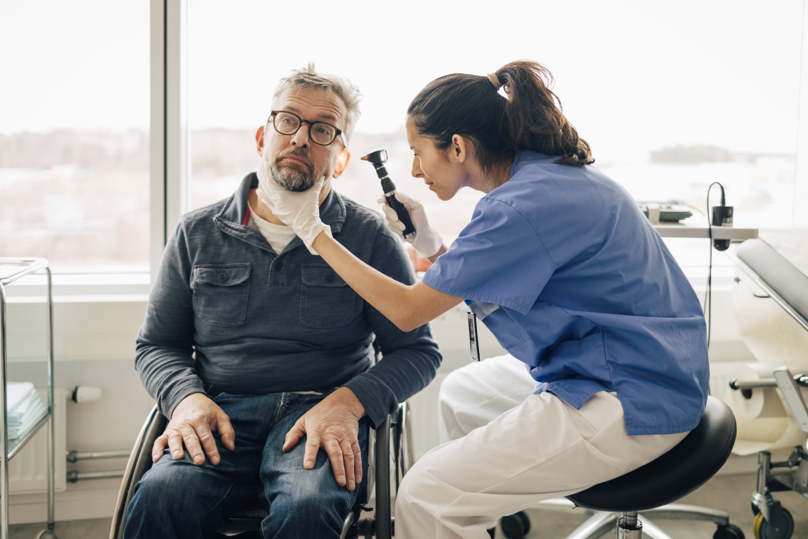 Health care provider using an instrument to look inside the ear of a male patient