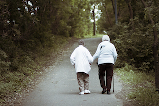 elderly woman walking with a cane outdoors