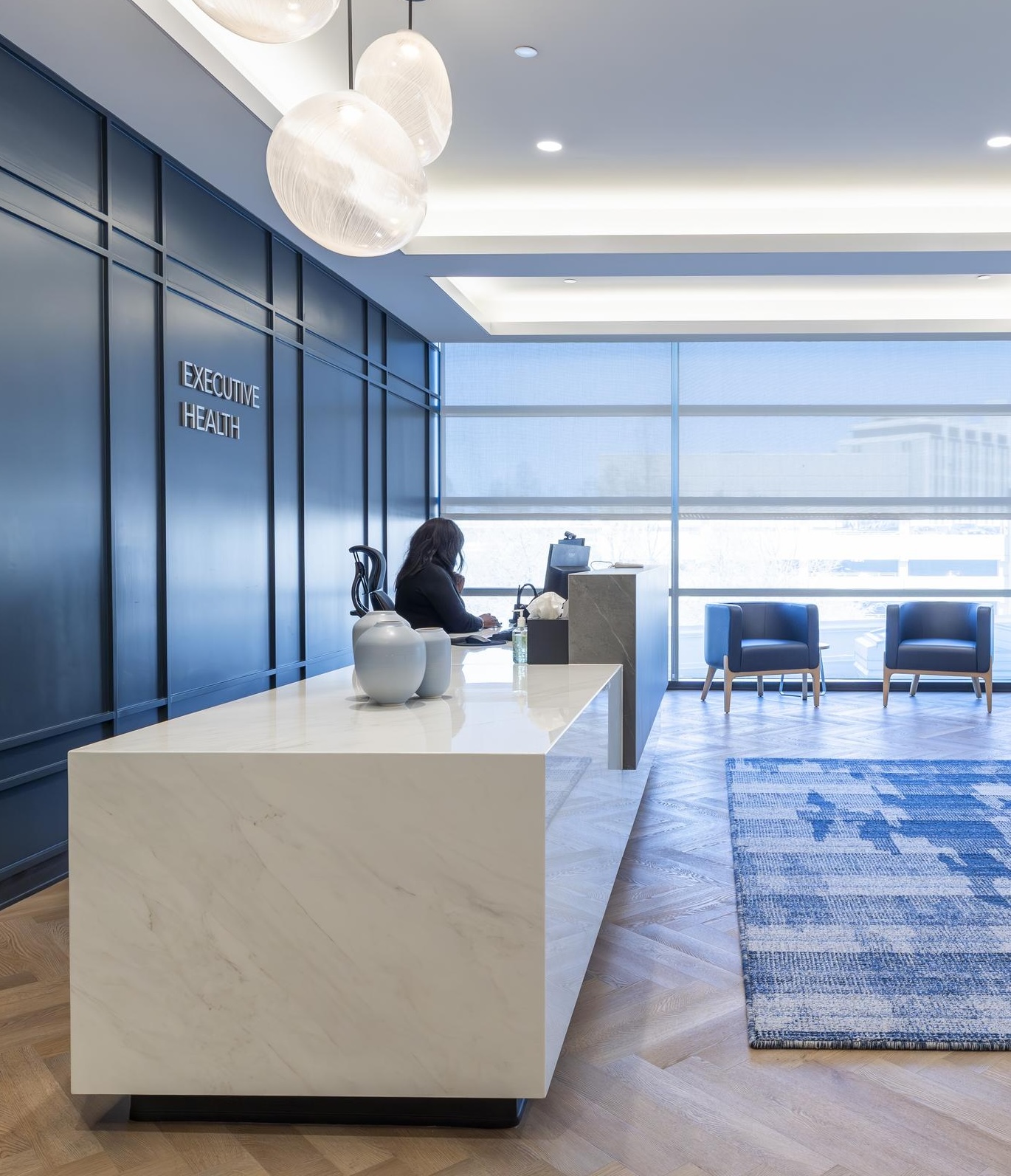 A modern and elegant lobby area with a reception desk, blue paneling, and comfortable seating.