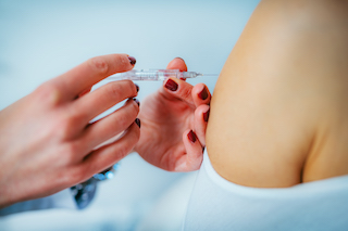 A woman receiving a flu shot from a doctor in a clinical setting.