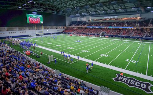 Ford Center: an indoor stadium with a green football field, surrounded by seated spectators.