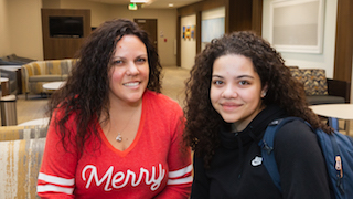 A woman and a young woman are smiling while sitting together.