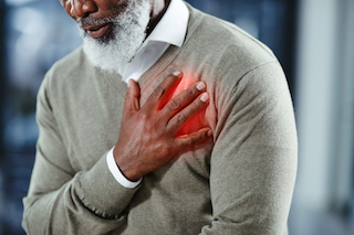 A distressed man holding his chest, indicating a heart attack