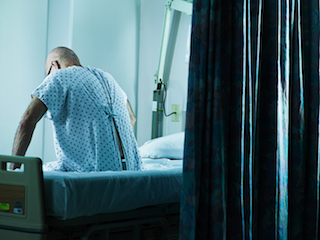 Patient sitting on a hospital bed in a dimly lit room