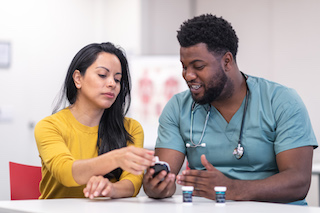 A healthcare professional explaining how to use a glucose meter to a patient