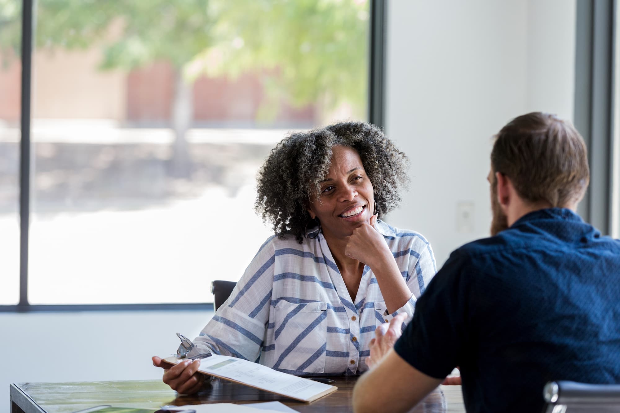 A woman and a man sit across from each other at a table, engaged in a thoughtful conversation