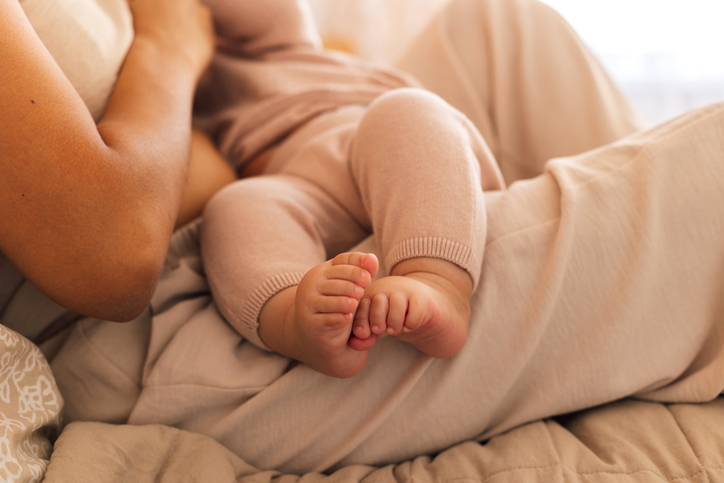 Babies feet resting on a mother's legs, indicating breastfeeding