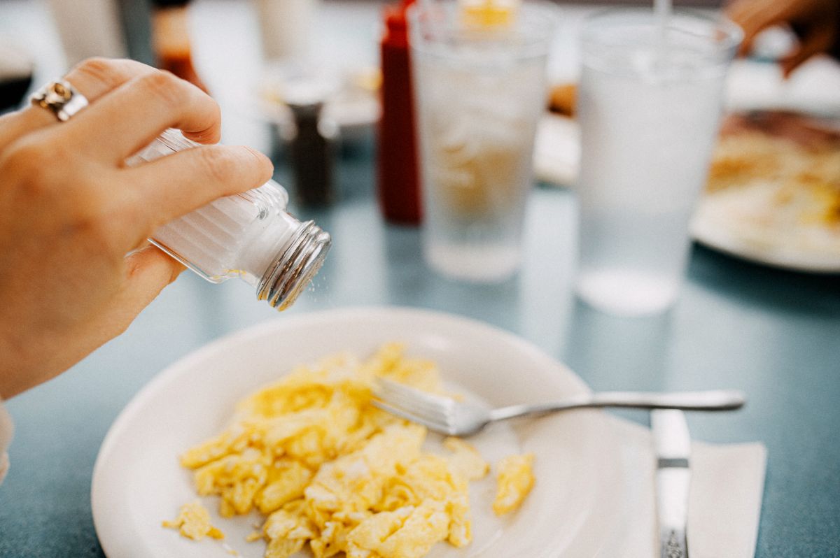 Diner pours salt on scrambled eggs.