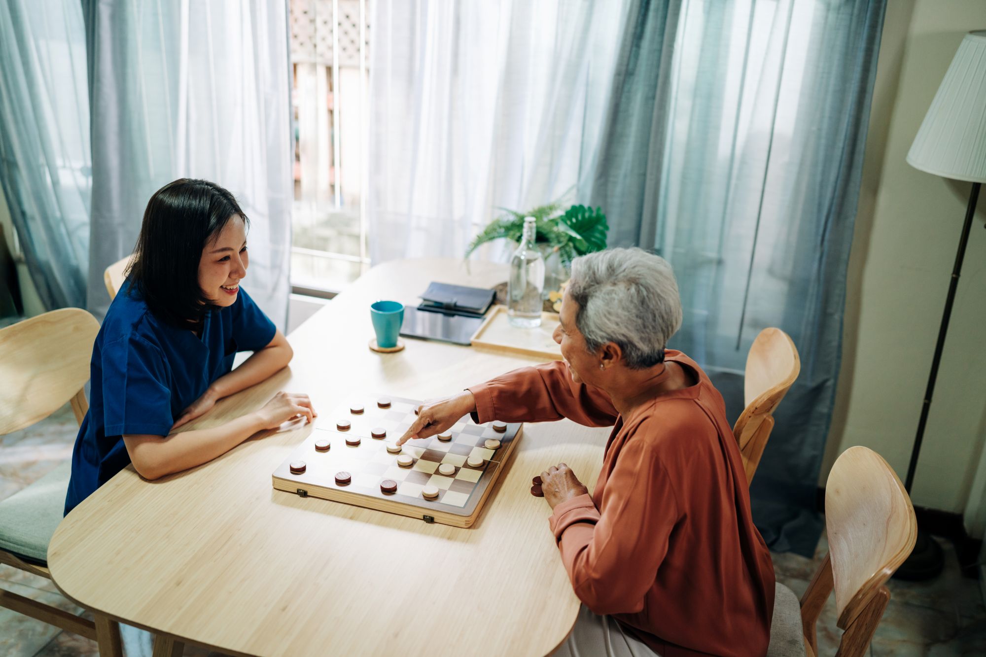 Caregiver playing a board game with an elderly patient.