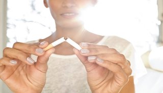Person breaking a cigarette in half to symbolize quitting smoking