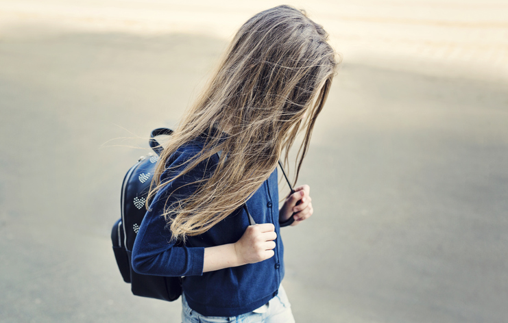 girl with long hair and a backpack walking alone
