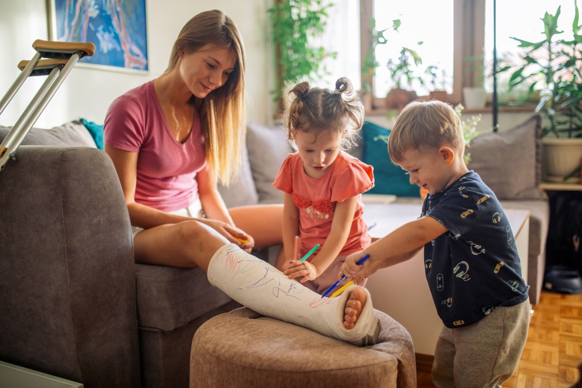Children of mother with broken leg draw on her cast.