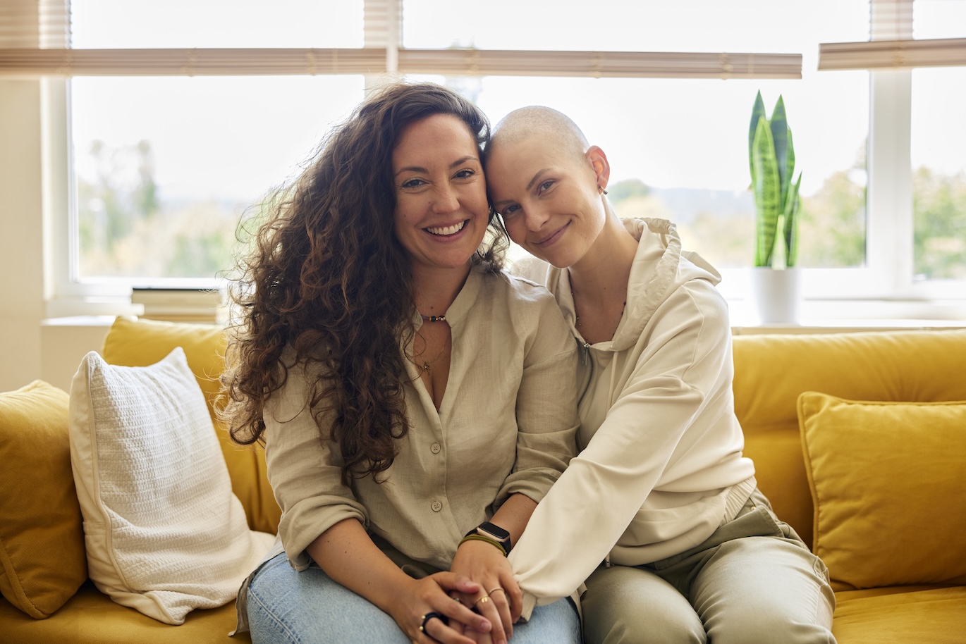 Best friend visiting Cancer Patient. Happy female friends sitting on sofa at home