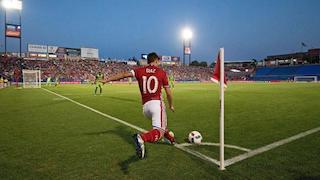 A soccer player about to kick the ball from the corner of the field.