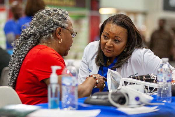 Two women engaged in a serious conversation at a table during Kwanzaa Fest