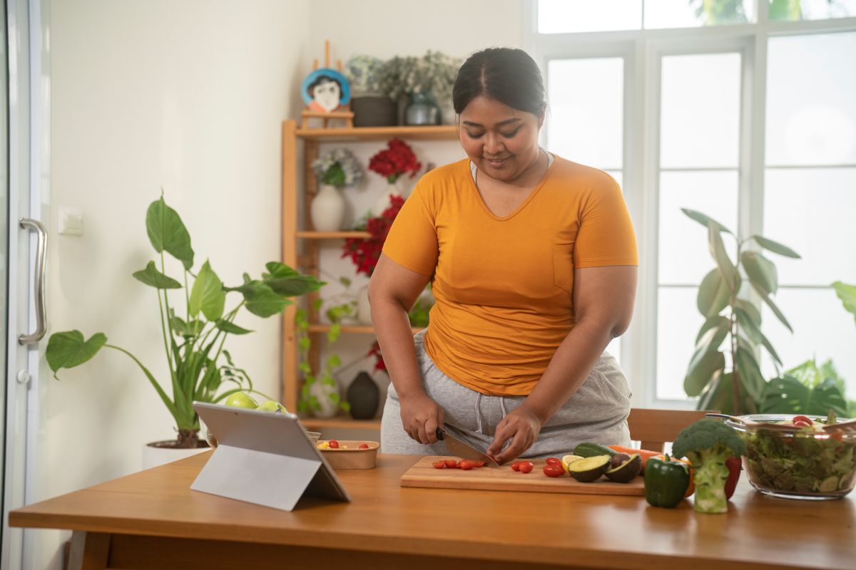 Woman cutting up vegetables in her kitchen.