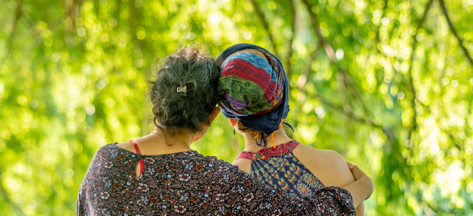 Two women looking at green trees, pictured from behind