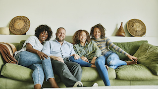 Happy family of four sitting together on a green couch