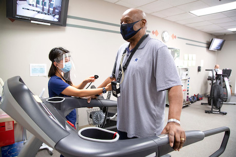 A patient in a face mask exercising on a treadmill.