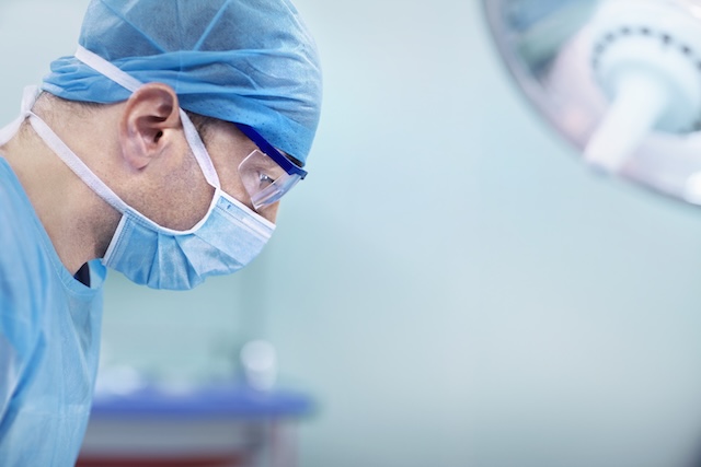Doctor looking down at patient in hospital operating room