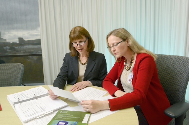 Two women sitting at a table with papers and a laptop