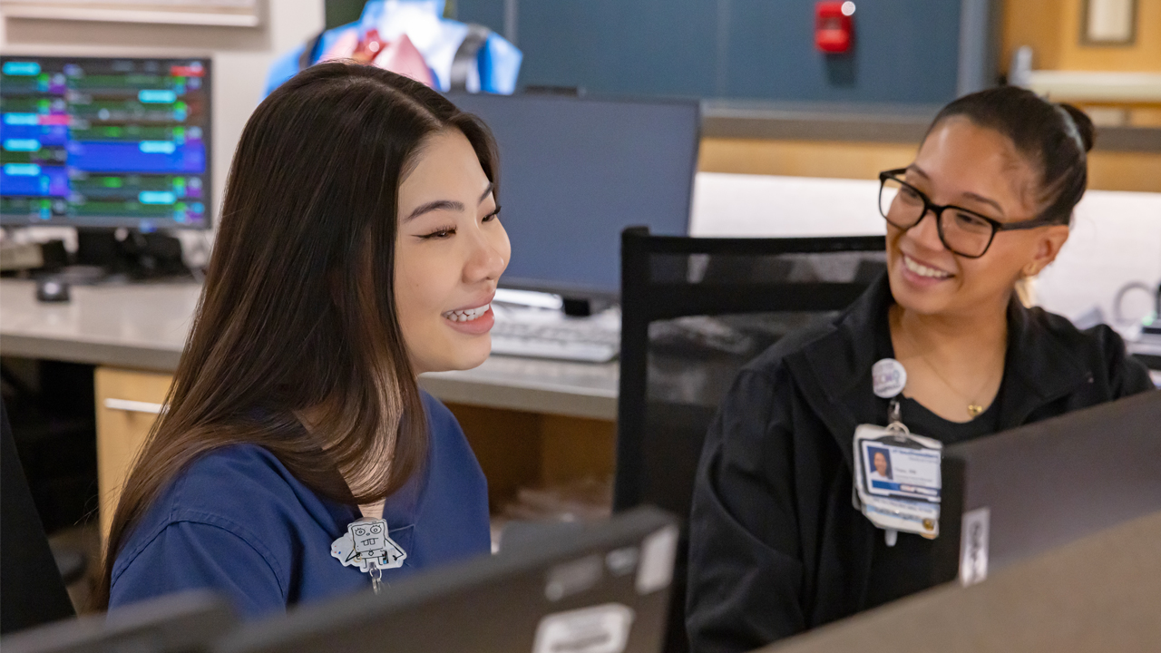 Two nurses smiling behind a desk