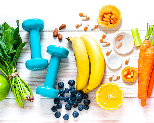 Fruits on white table next to blue hand weights