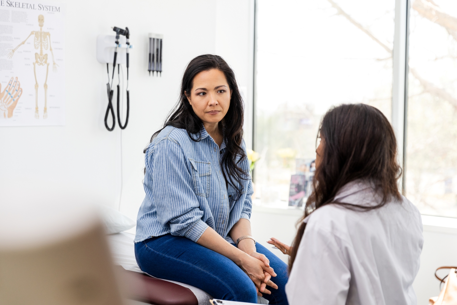 A woman on exam table chatting with a female doctor