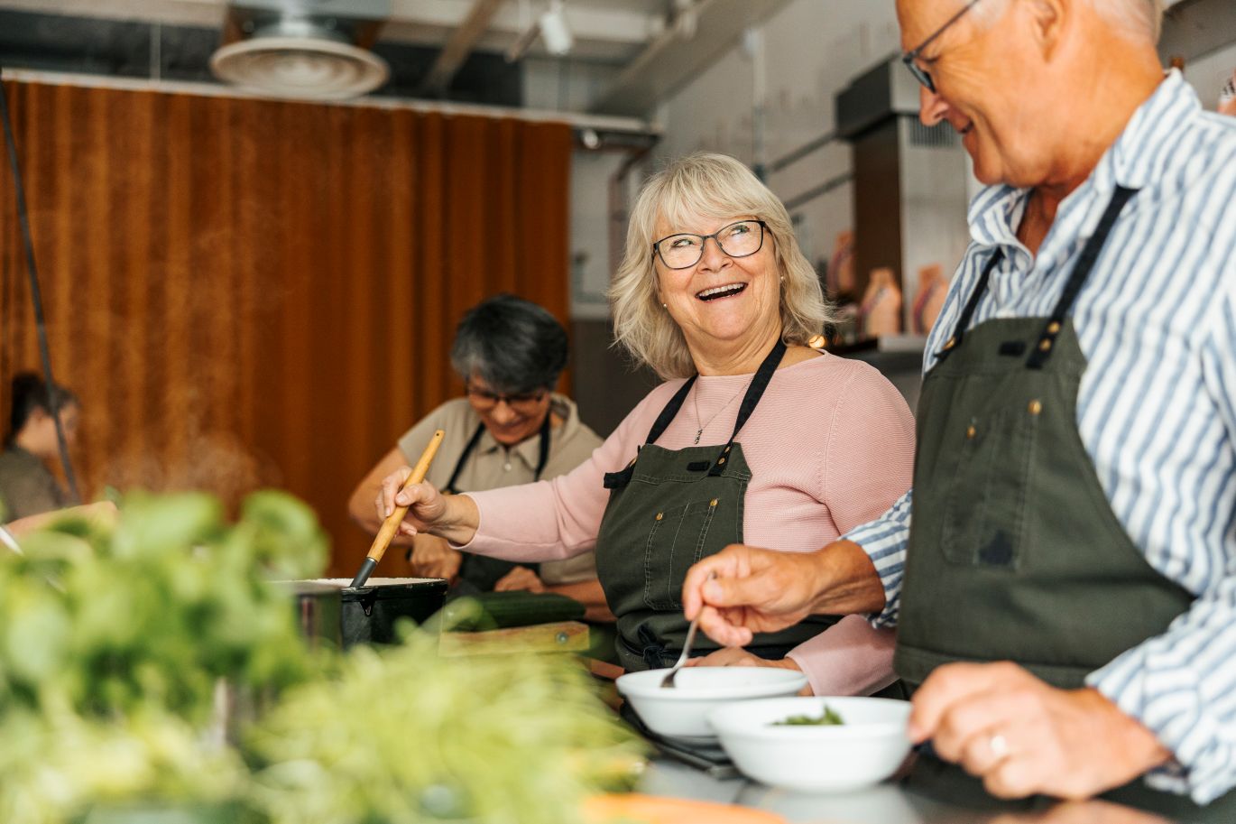 Senior citizens cook together in a social setting.