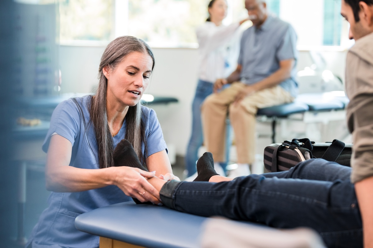 Physical therapist works on man's ankle during physical therapy session
