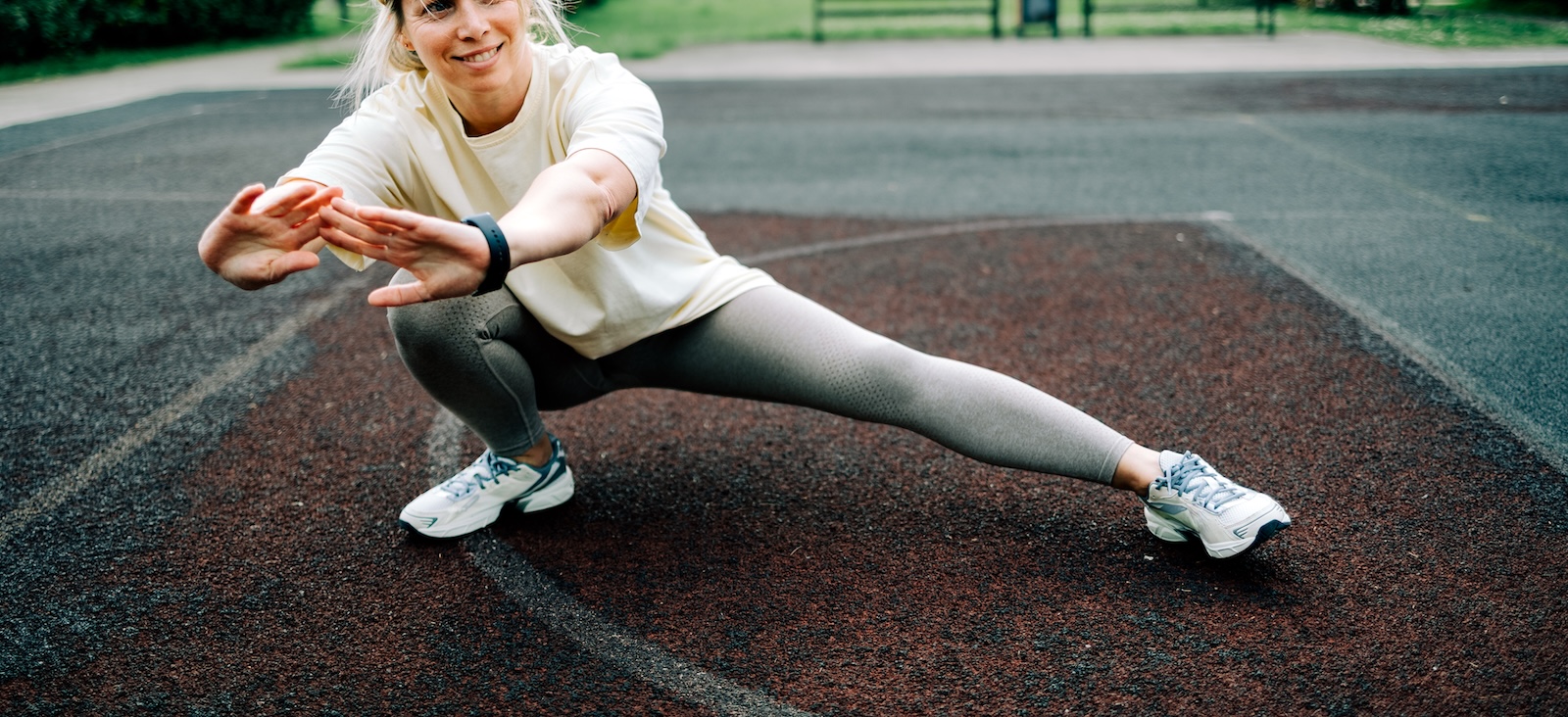 Smiling mature woman stretching her leg in residential neighborhood