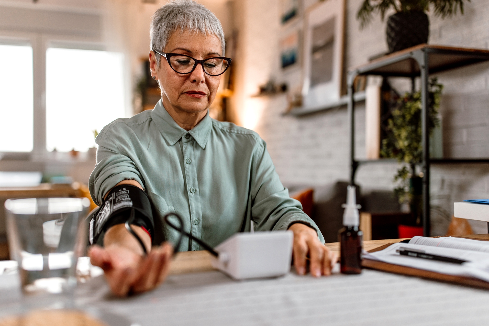 Woman seated at table and getting blood pressure reading